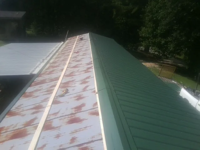 Old rusted panels beside newly installed green metal roofing — Wind Damage Roof Repair by Roofing Brothers in Pillager