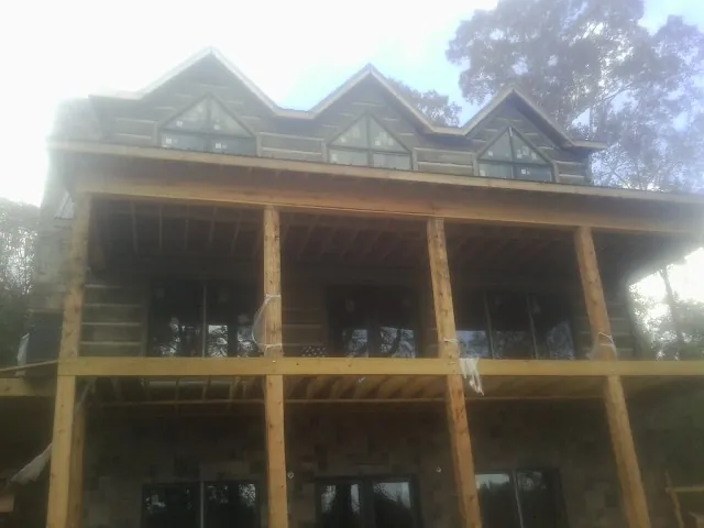 Dormers and porch framing on a large log home under construction — Roof Coating work by our crew in Pillager