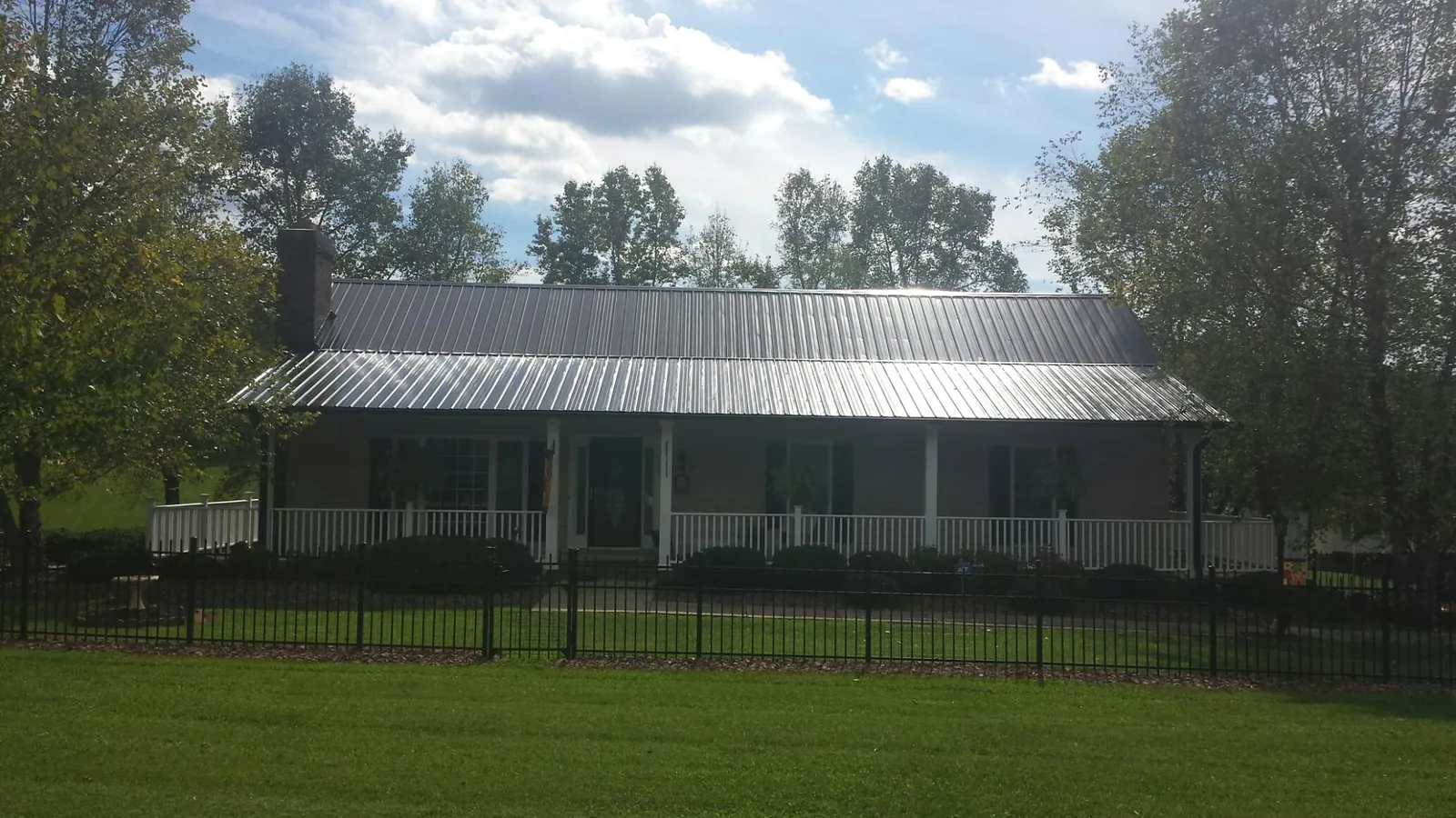 Gray metal roof on a brick ranch with a full width front porch — Gutter Guard Installation work by our crew in Pillager