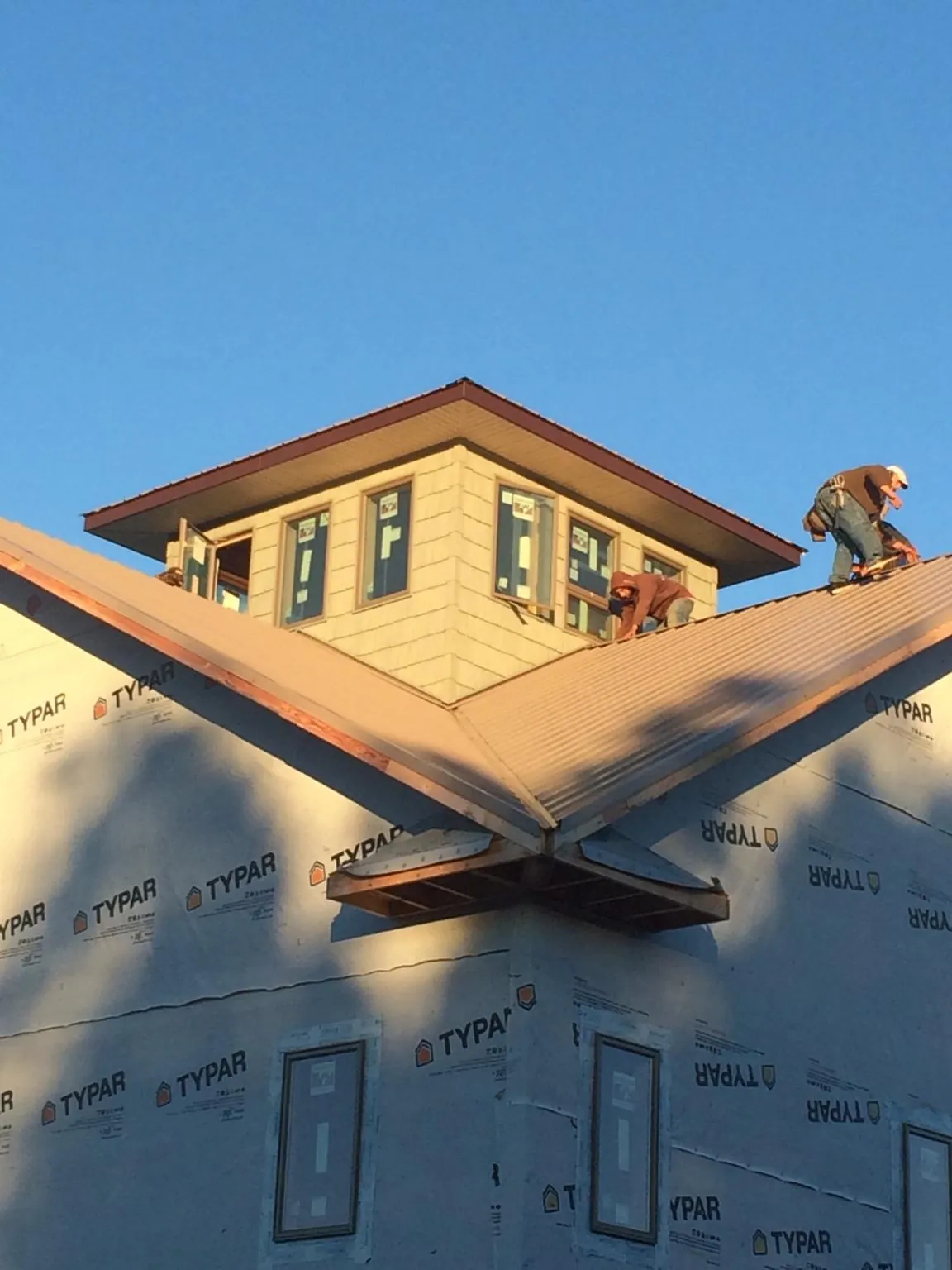 Roofers working around a rooftop cupola on a new metal roof at sunset — Roof Waterproofing in Pillager by Roofing Brothers